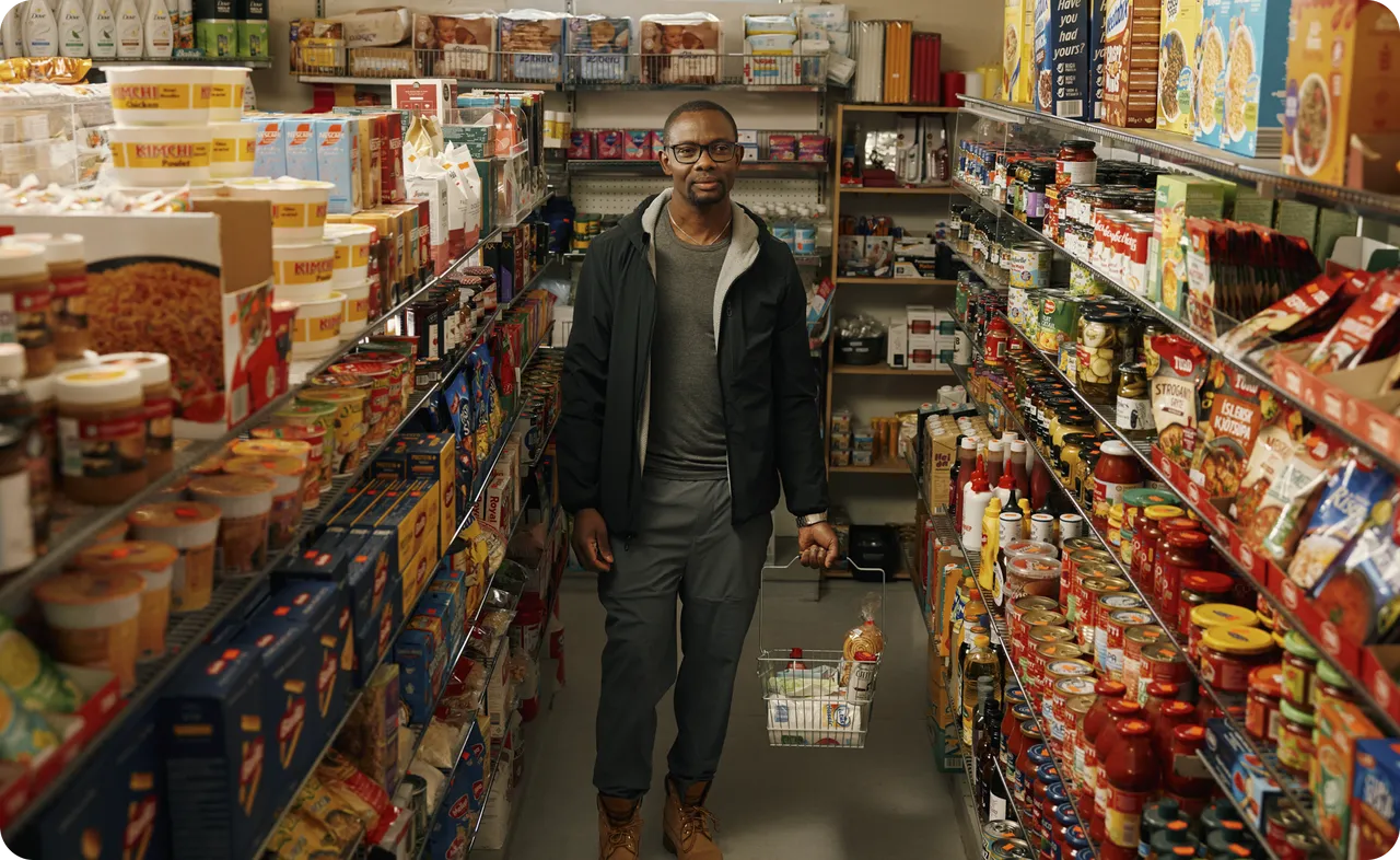 Someone walks down a grocery store aisle carrying a shopping basket